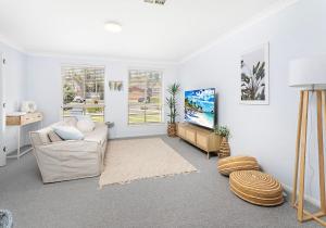 uma sala de estar com um sofá e uma televisão em Drifters em Gerringong