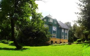 a large green house in a field of grass at Pensjonat Eldorado in Świeradów-Zdrój