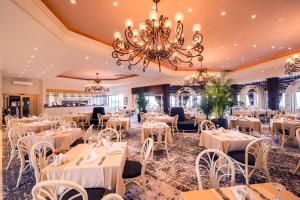 un restaurant avec des tables et des chaises blanches et un lustre dans l'établissement The Olive Tree Hotel, à Kyrenia