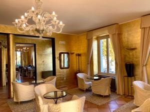 salon z żyrandolem i białymi krzesłami w obiekcie Caroline Hotel w mieście Brusimpiano