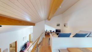 Palois Family Apartment Centre Lenzerheide في لينتسرهايدي: غرفة معيشة بجدران بيضاء وسقف خشبي