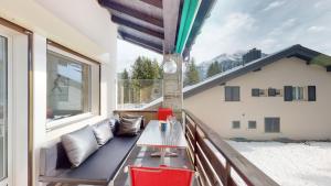 a balcony with a bench and a table and a window at Palois Family Apartment Centre Lenzerheide in Lenzerheide