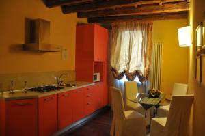 a kitchen with red cabinets and a table with a sink at Piazza Nova Guest House in Ferrara