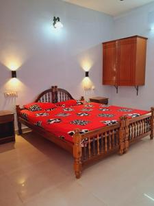 トリバンドラムにあるAnamika Holiday homeのベッドルーム1室(大型木製ベッド1台、赤毛布付)