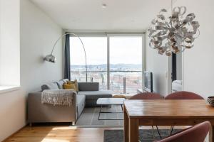 a living room with a couch and a table and a chandelier at Hoch hinaus, neu und stilvoll mit Pool am Dach in Vienna