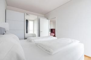 a white bedroom with two beds and a mirror at Hoch hinaus, neu und stilvoll mit Pool am Dach in Vienna +43 photos