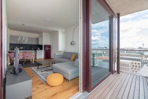 a living room with a couch and a kitchen and a balcony at Hoch hinaus, neu und stilvoll mit Pool am Dach in Vienna