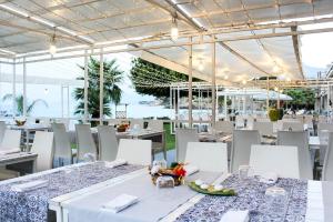 ein Restaurant mit weißen Tischen, weißen Stühlen und einem Tisch in der Unterkunft Hotel Tonnara Trabia in Trabia