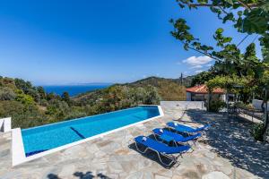 a swimming pool with lounge chairs and the ocean at Villa Pasifika in Loutraki