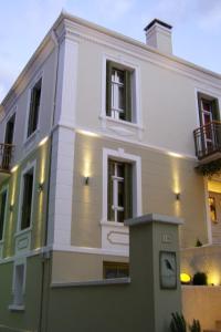 a white building with a clock in front of it at room "butterfly" in a neoclassical house in Kastoria