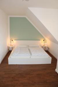 Auszeit am Meer في زيروف: سرير أبيض في غرفة مع طاولتين جانبيتين