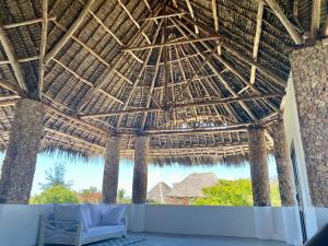 a pavilion with a couch under a straw roof at Mumbi villa in Watamu
