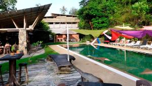 a swimming pool with a tent and a building at Bamboo Cottage Langkawi in Pantai Cenang
