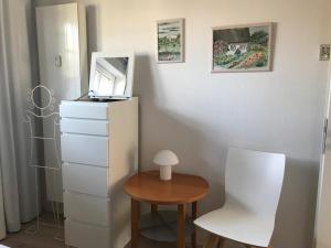 Zimmer mit einer Kommode, einem Tisch und einem Stuhl in der Unterkunft Ferienwohnung *Reethuk* in Norddorf