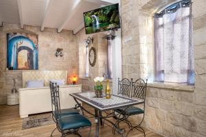 einen Tisch und Stühle in einem Zimmer mit einer Steinmauer in der Unterkunft Heart Mansion Rashbi compound in Safed