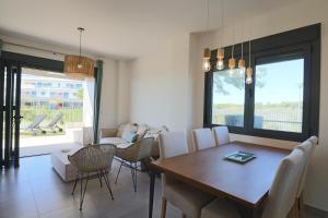 a dining room and living room with a table and chairs at Apartamento Familiar La Reserva in El Rompido