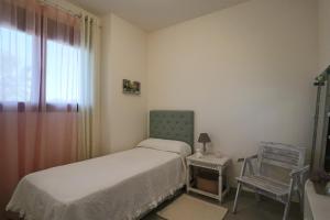 niewielka sypialnia z łóżkiem i krzesłem w obiekcie Apartamento Familiar La Reserva w mieście El Rompido