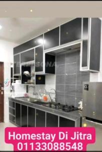 a kitchen with stainless steel appliances and a pink poster at Mahsuri Homestay in Jitra