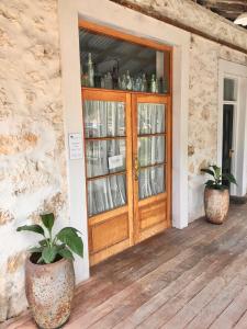 une porte en bois sur une terrasse couverte avec deux plantes en pot dans l'établissement Fremantle Boutique Accommodation - Maand Up, à Fremantle