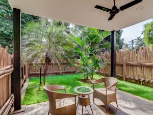 a patio with a table and chairs and a garden at Acron Seaway Resort in Candolim