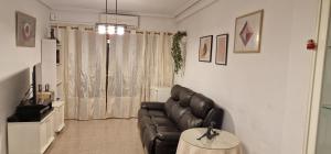a living room with a black leather couch and a table at PalmeraV in Santa Pola