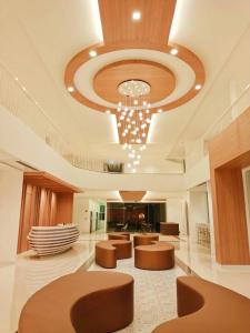 a lobby with brown chairs and a chandelier at M CASA HOTEL PATTAYA in Nong Prue