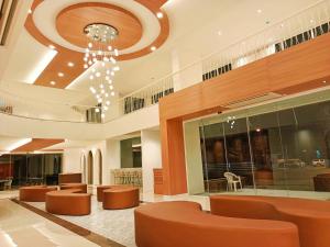 a lobby with brown chairs and a chandelier at M CASA HOTEL PATTAYA in Nong Prue