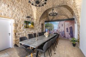 a dining room with a stone wall and a table and chairs at The Antiquity Heart Mansion in Safed
