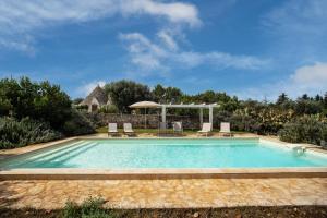 a swimming pool with chairs and a gazebo at Country House da Già in Ostuni