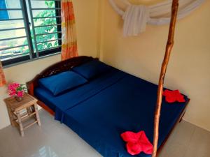 a bedroom with a bed with blue sheets and red flowers at Baloo Guesthouse in Koh Rong Sanloem