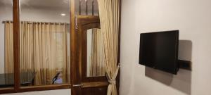 TV de pantalla plana colgada en una pared junto a una ventana en Whispering Pinewoods, en Pīrmed