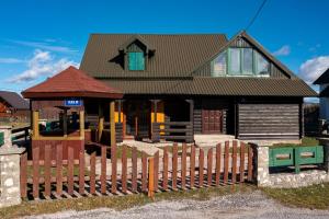 a house with a wooden fence in front of it at Village Villa North Wind in Žabljak