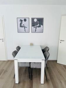 una mesa y sillas blancas en una habitación con cuadros en la pared en Zollernalb-Apartment MG, en Albstadt