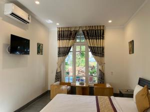 1 dormitorio con 2 camas, mesa y ventana en Khách sạn Hương Mê en Buon Ma Thuot