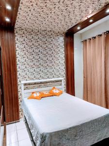 a bedroom with a bed with a patterned wall at Casa aconchegante in Campo Grande