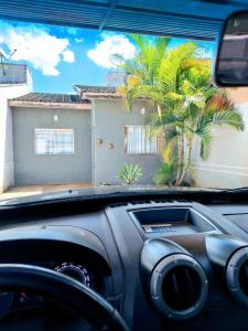 a car driving past a house with a palm tree at Casa aconchegante in Campo Grande