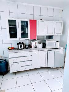 a white kitchen with white cabinets and white appliances at Casa aconchegante in Campo Grande