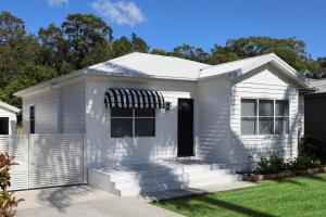 a white house with an awning at The Heads House in Shoalhaven Heads