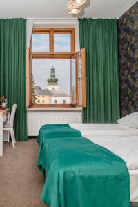 a bedroom with a bed with green curtains and a window at The Old Townhouse in Krosno