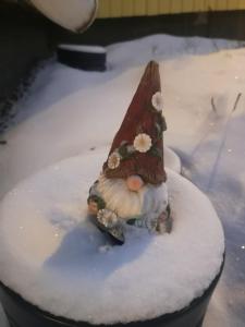 una statuina di uno gnomo nella neve di Mummon saunamökki a Helsinki