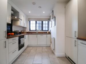 a kitchen with white cabinets and a tile floor at 8 Oaks Court in Leiston