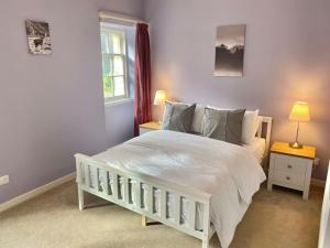 a bedroom with a white bed and two night stands at Charming 3/4 bedroom semi-detached cottage. in Carberry