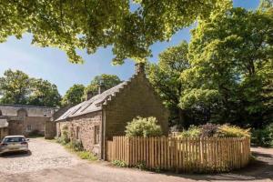 CarberryにあるCharming 3/4 bedroom semi-detached cottage.の古石造りの建物(柵付)と、外に駐車した車