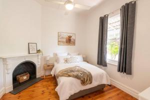 a white bedroom with a bed and a fireplace at Newly renovated, Kennedy Cottage - close to CBD in Bendigo