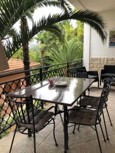 una mesa y sillas en un balcón con palmeras en Apartment Nika en Lovran
