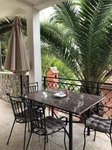una mesa y sillas en un patio con una palmera en Apartment Nika en Lovran