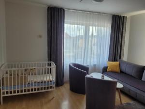 a baby room with a couch and a crib at Apartman centrum v súkromí in Martin
