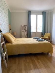 a bedroom with a large bed with a yellow blanket at Appart 90m2 lumineux, centre, vue église penchée in Caen