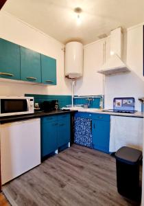 a kitchen with blue cabinets and white appliances at Appart plein centre, vue cathédrale, fibre in Lisieux