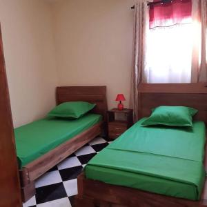 two green beds in a room with a checkered floor at VIllAPPART ( appartement au rc) in Antananarivo